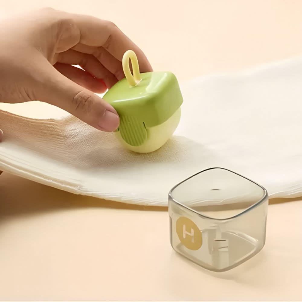 Hand using mini lint roller on white fabric, with detachable dust container placed beside
