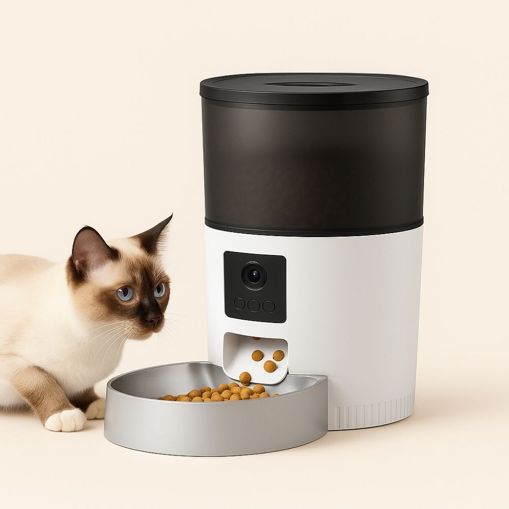 Cream-colored cat sitting beside a smart pet feeder with a camera, looking curiously at the food tray, against a soft beige background.