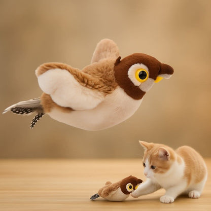 Plush bird toy flying above a playful kitten reaching out on a wooden surface.